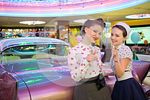 Two beautiful girls in retro dress gesture and