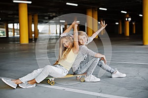 Two beautiful girls skateboarding, having fun and playing in the parking lot