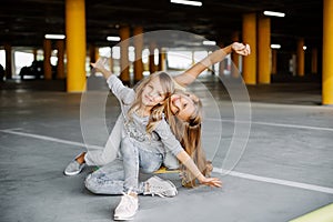 Two beautiful girls skateboarding, having fun and playing in the parking lot