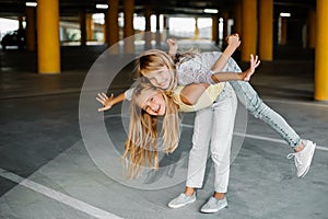 Two beautiful girls skateboarding, having fun and playing in the parking lot