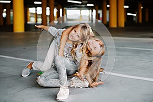 Two beautiful girls skateboarding, having fun and playing in the parking lot