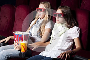 Two beautiful girls watching a movie at the cinema