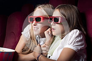 Two beautiful girls watching a movie at the cinema