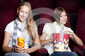 Two beautiful girls watching a movie at the cinema