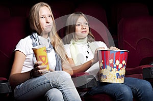 Two beautiful girls watching a movie at the cinema