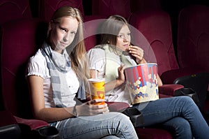 Two beautiful girls watching a movie at the cinema