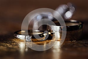 Two beautiful golden wedding rings and earrings on a wooden background.