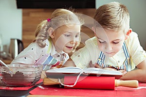 Two beautiful and happy children exploring recept before preparing christmas cookies