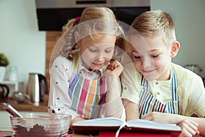 Two beautiful and happy children exploring recept before preparing christmas cookies