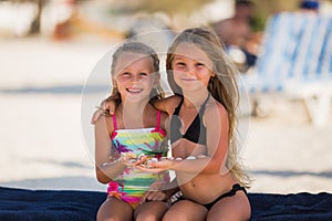 Two beautiful happy girl with shells in their hands photo