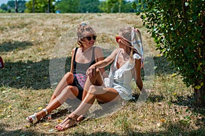 Two beautiful happy women on the grass relaxing outdoors in summer.