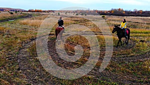 Two beautiful horses with equestrians are going in circle on the field