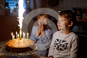 Two beautiful kids, little preschool boys celebrating birthday and blowing candles