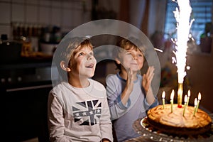 Two beautiful kids, little preschool boys celebrating birthday and blowing candles