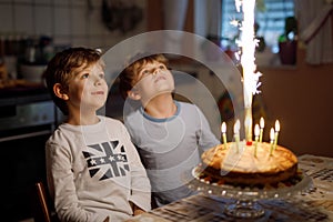 Two beautiful kids, little preschool boys celebrating birthday and blowing candles