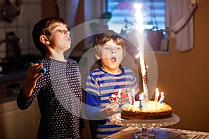 Two beautiful kids, little preschool boys celebrating birthday and blowing candles