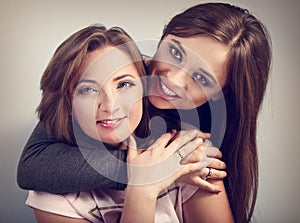 Two beautiful laughing girl friends hugging with love with rings