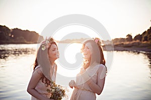 Two beautiful laughing sisters in the rays of sunset