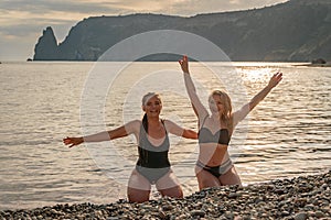 Two beautiful lgbt lesbian female friends relax and happy at the beach sitting on the sand wearing swimsuit. Travel and