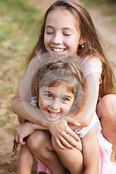 Two beautiful little girls embracing and laughing at the seaside