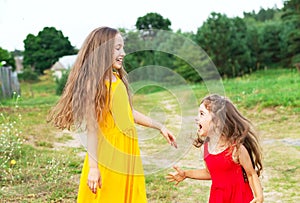 Two beautiful little girls playing and smiling at sunny summer d