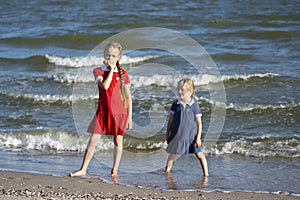 Two beautiful little sisters play and have fun on the beach