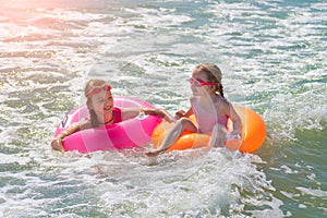 Two beautiful little sisters play and have fun in sea water on the beach. Vacation or holiday concept. Children girls