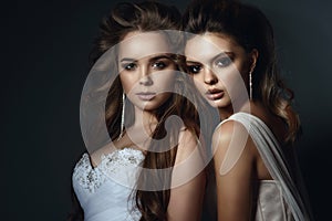 Two beautiful models with perfect take up and hairstyle wearing wedding dresses and luxurious earrings