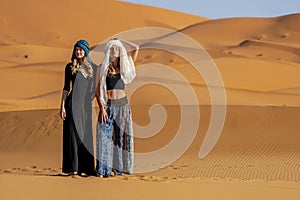 Two Beautiful Models Pose In The Sand Dunes In The Great Sahara Desert In Morocco, Africa