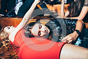 Two beautiful relaxed women lying down on the floor and taking r