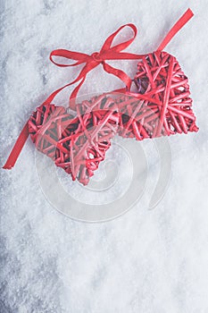 Two beautiful romantic vintage red hearts tied together with ribbon on white snow background. Love and St. Valentines Day concept