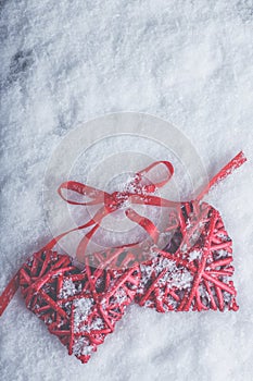 Two beautiful romantic vintage red hearts tied together with ribbon on white snow background. Love and St. Valentines Day concept