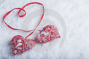 Two beautiful romantic vintage red hearts tied together with ribbon on white snow background. Love and St. Valentines Day concept