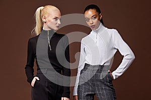 Two beautiful sexy woman long brunette blond hair glamour model wear pants and sweater work office style dress code accessory