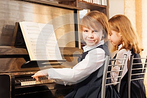 Two beautiful small girls playing piano indoors