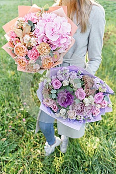 Two beautiful spring bouquet. Young girl holding a flowers arrangements with various of colors. Bright dawn or sunset