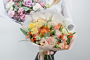 Two beautiful spring bouquet. Young girl holding a flowers arrangements with various of colors. white wall.