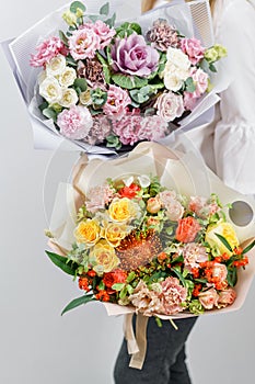 Two beautiful spring bouquet. Young girl holding a flowers arrangements with various of colors. white wall.