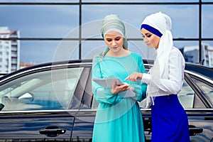 Two beautiful and successful european muslim business women entrepreneur in stylish hijab and turban holding paper