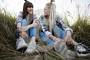 Two beautiful twin girls make style in the field at sunset