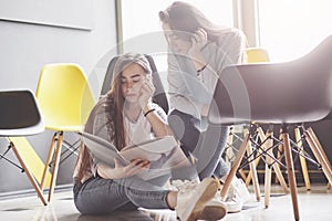 Two beautiful twin girls spend time read a book in library in the morning. Sisters relaxing in a cafe and having fun