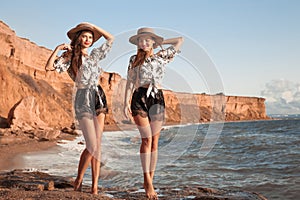 Two beautiful twins girl in straw hat having fun on the beach enjoying life, summer sunset outdoor portrait. People Girlfriend