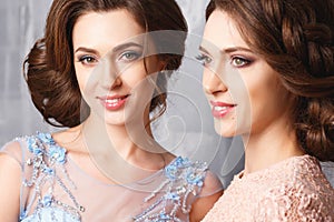 Two beautiful twins young women in luxury dresses, pastel colors