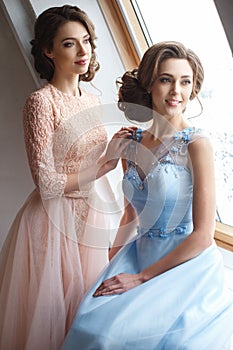 Two beautiful twins young women in luxury dresses, pastel colors