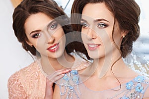 Two beautiful twins young women in luxury dresses, pastel colors