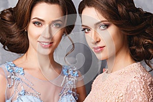 Two beautiful twins young women in luxury dresses, pastel colors
