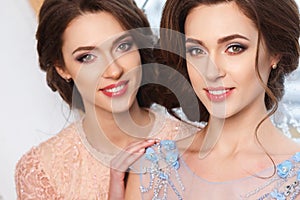 Two beautiful twins young women in luxury dresses, pastel colors