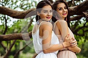 Two beautiful twins young women in summer dresses near blooming lilac