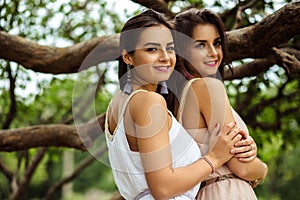 Two beautiful twins young women in summer dresses near blooming lilac