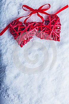 Two beautiful vintage red hearts tied together with a ribbon on a white snow background. Love and St. Valentines Day concept.